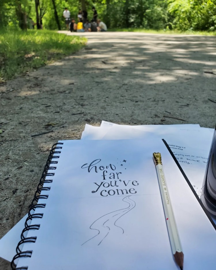 Sketchbook lettering stating "how far you've come" with students in the far back